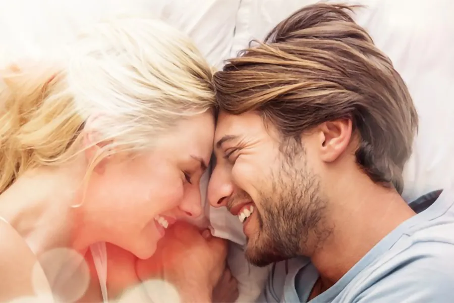 Acoustic-Pressure-Wave-for-ED-Clinic A sun-dappled couple lie in bed smiling excitedly at each other. Get Acoustic Pressure Wave for Erectile Dysfunction treatment from Regenerative Medical Institute in Greenville.