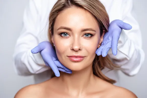 Botox-Doctor Close up of a woman's face with a doctor wearing rubber gloves standing behind her holding his hands around her face to show the amazing Botox treatment from Regenerative Medical Institute in Greenville.