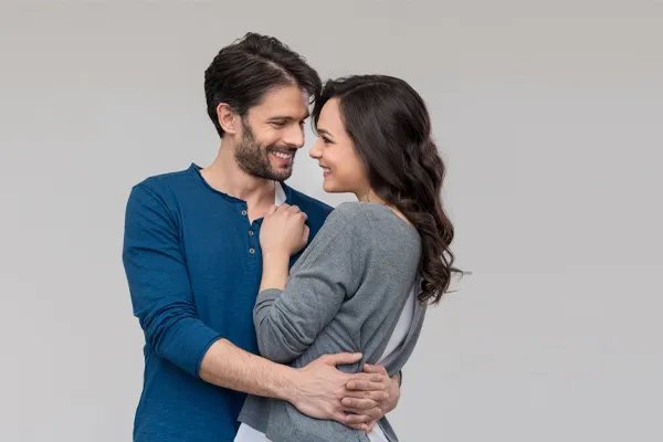 Erectile-Dysfunction-Doctor A man in a blue shirt embracing a woman in a gray shirt smiles due to his successful erectile dysfunction care from Regenerative Medical Institute in Greenville.
