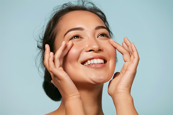 Exosome-Facial-Clinic Woman smiles grandly while feeling her smooth skin. Schedule exosome facial therapy with Regenerative Medical Institute in Greenville.