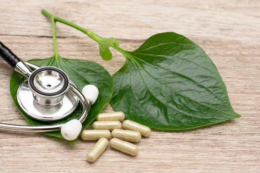 Integrative-Medicine-Clinic A stethoscope, leaves, and medicine capsules on a wood table, representing Integrative Medicine provided by Regenerative Medical Institute in Greenville.