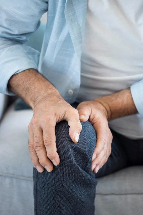 Osteoporosis-Pain A close-up of a man holding his knee while experiencing pain from osteoporosis. Get osteoporosis treatment from Regenerative Medical Institute in Greenville.