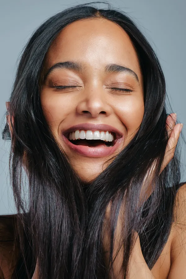 PRP-for-Hair-Loss-Treatment A beautiful latin woman smiles and runs her fingers through her long, beautiful hair, happy with her PRP for hair loss and restoration treatment from Regenerative Medical Institute in Greenville.