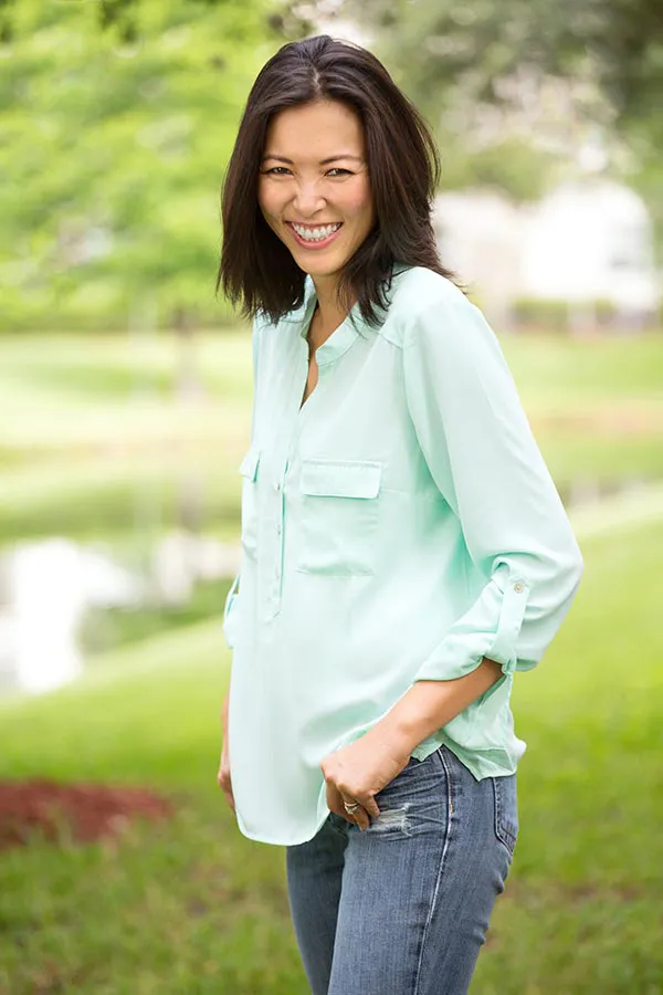 Perimenopause-Treatment A middle-aged brunette woman in a light green button-up shirt stands outside smiling, happy with her perimenopause treatment from Regenerative Medical Institute in Greenville.
