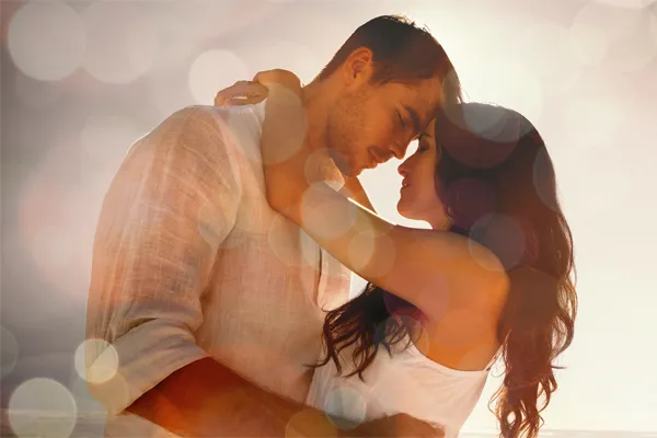 A couple in linen shirts standing in a sparkling light embraces each other with their foreheads touching and eyes closed, happy with their sexual wellness treatments from Regenerative Medical Institute in Greenville.