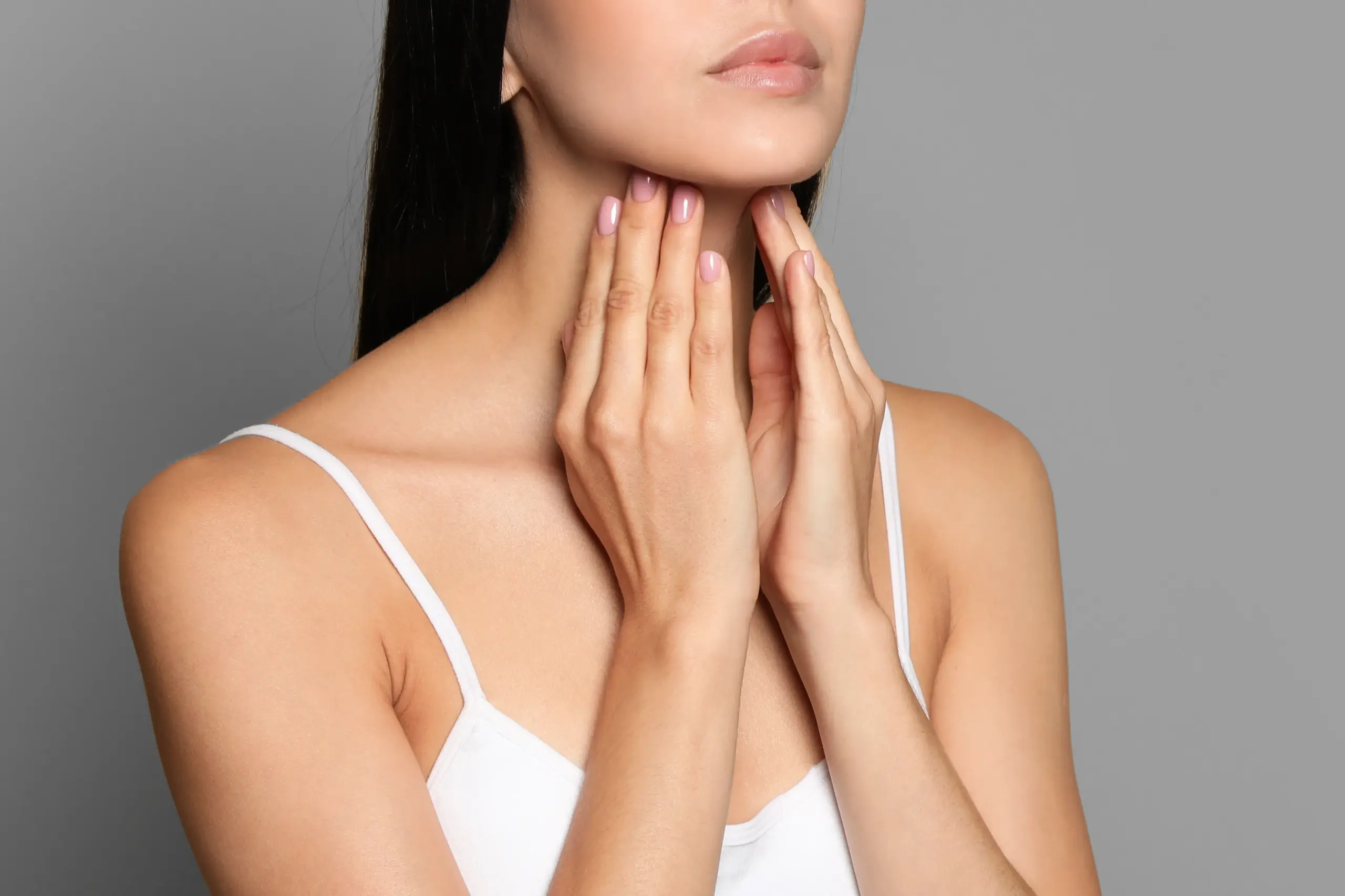 Thyroid-Doctor A woman in a white tank top touches her neck looking for signs of thyroid disorder. Get help for thyroid disorders from Regenerative Medical Institute in Greenville.
