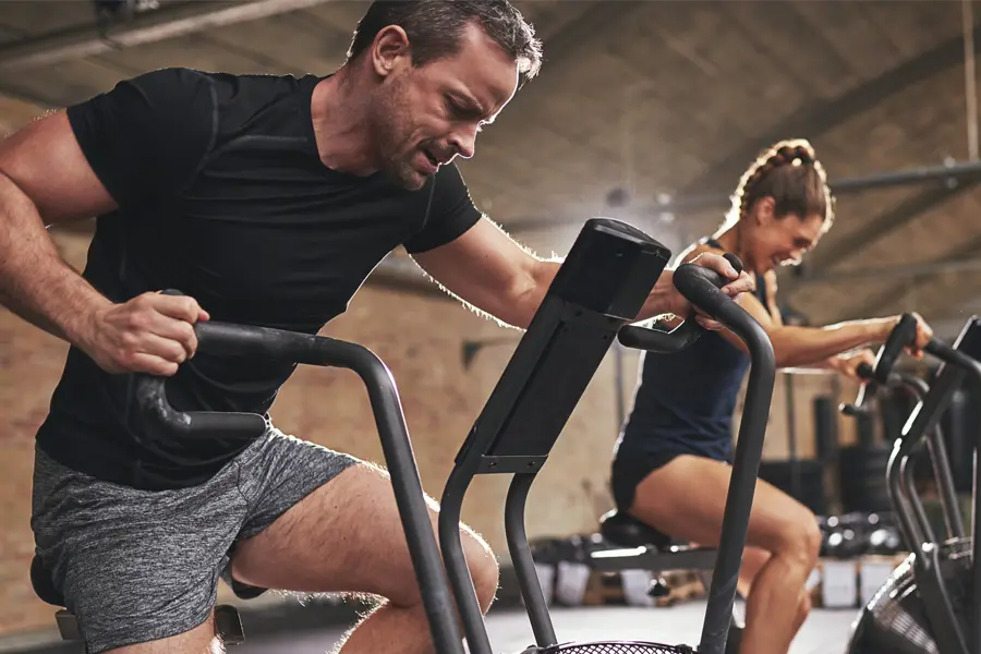 Tirzepatide-Doctor A couple in a brick gym work as hard as they can on exercise bikes, inspired by successful Tirzepatide treatment from Regenerative Medical Institute in Greenville.
