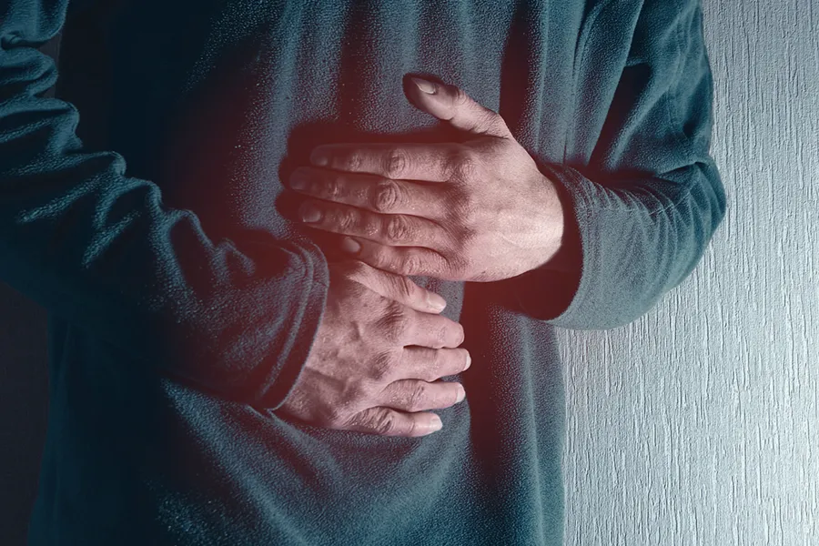 Ulcerative-Colitis-Clinic Close-up of the midsection of a man in a green sweater clutching his gut in pain. Get treatment for Ulcerative Colitis from Regenerative Medical Institute in Greenville.