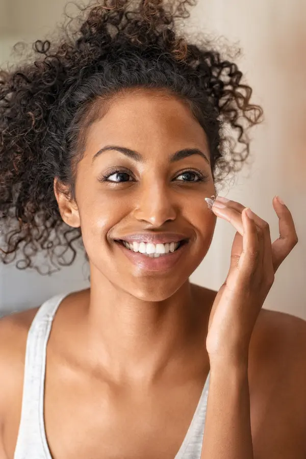 microneedlingmesotherapy-treatment Close-up of a woman smiling into the mirror while rubbing facial cream on her cheek. Receive Microneedling with Mesotherapy from Regenerative Medical Institute in Greenville.